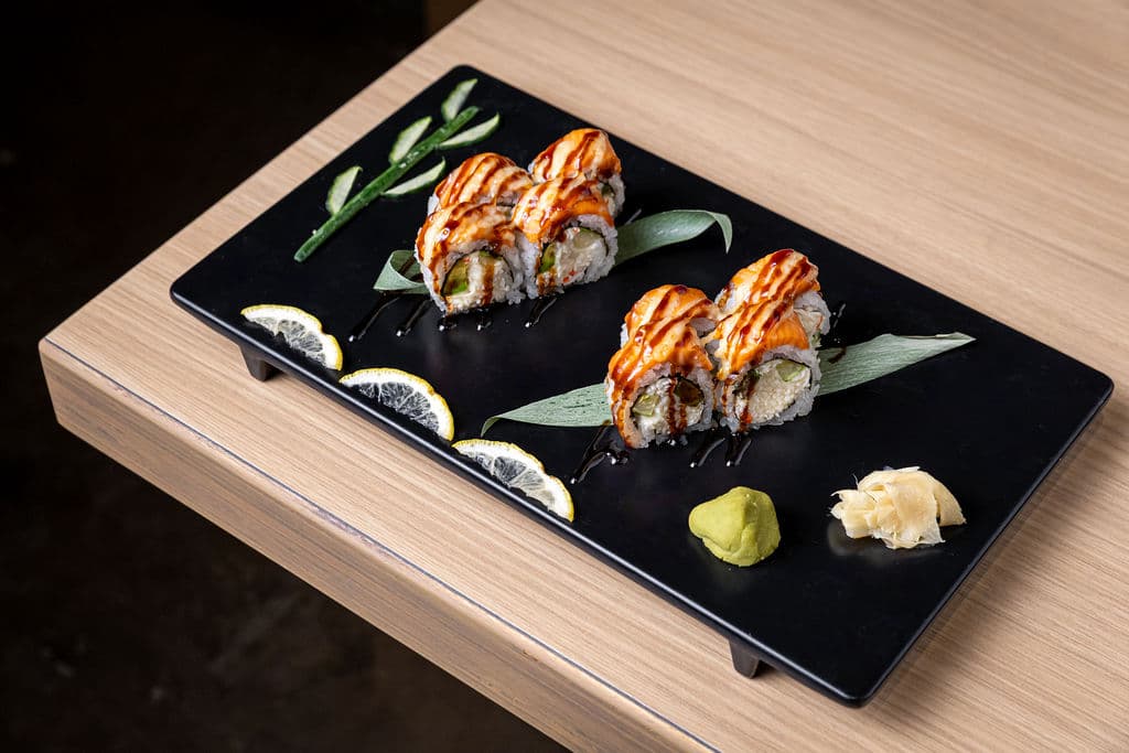 Baked Salmon Roll. California roll base topped with salmon, baked with house sauce, and drizzled with eel sauce.